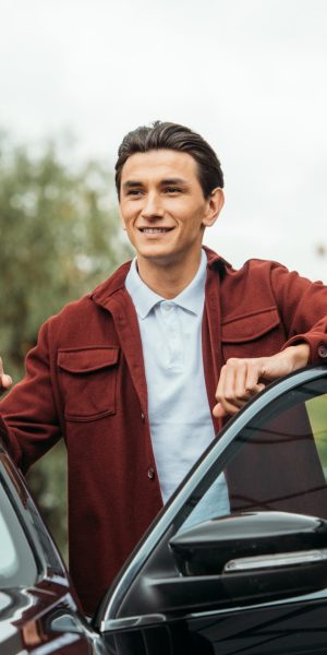 Smiling taxi driver beside open car door